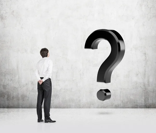 Homme s'interrogreant devant un point d'interrogation géant